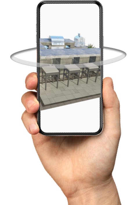 A hand holding a phone displaying a Belgard room superimposed over a verdant backyard